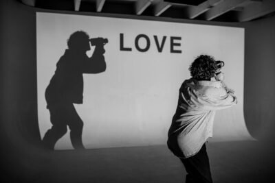 Creative monochrome photograph capturing a shadow and 'Love' projection in a studio.