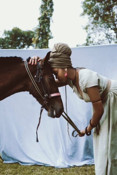 A woman affectionately interacts with a horse in an outdoor setting, embodying connection and tranquility.