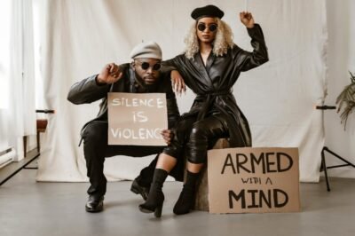 Black couple in studio with protest signs advocating peace and awareness.