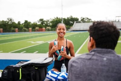 Young woman holding running shoes at track