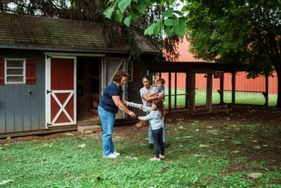 Family interacts with a woman near a shed.