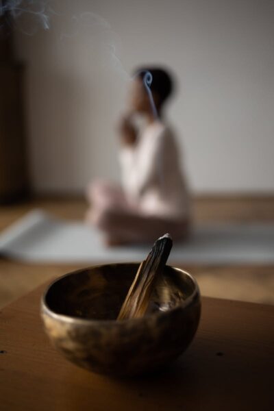 A serene moment of mindfulness featuring incense in a singing bowl during yoga practice.